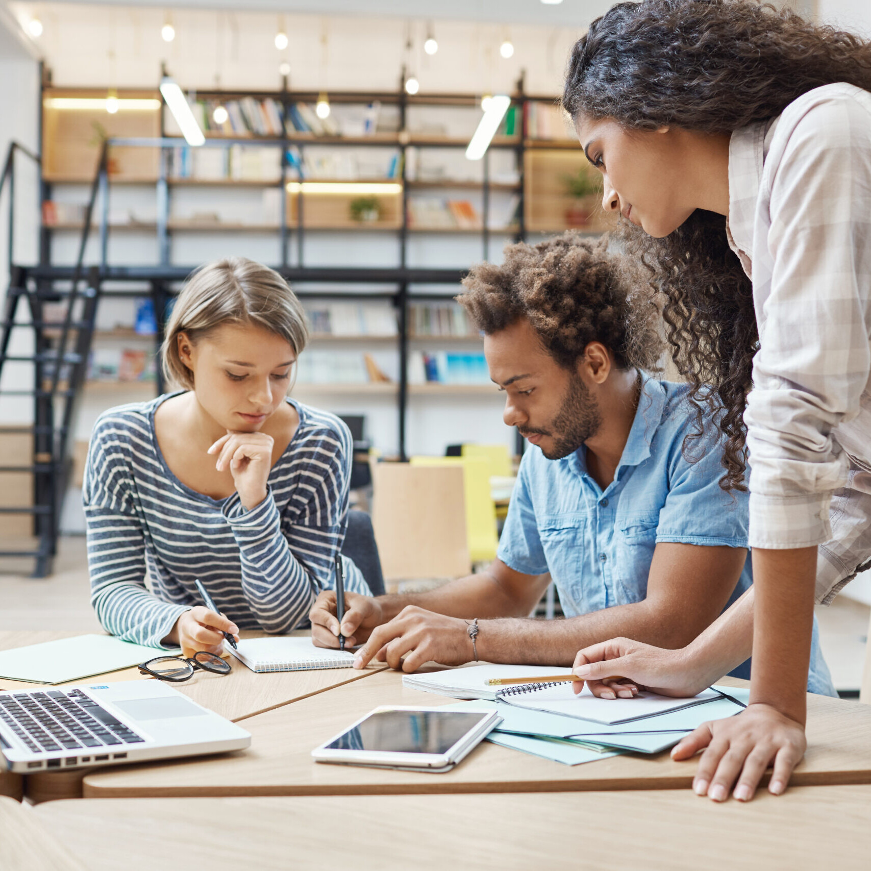 Small business employees using HRIS software to manage employee data, payroll, and benefits administration in a modern coworking space.