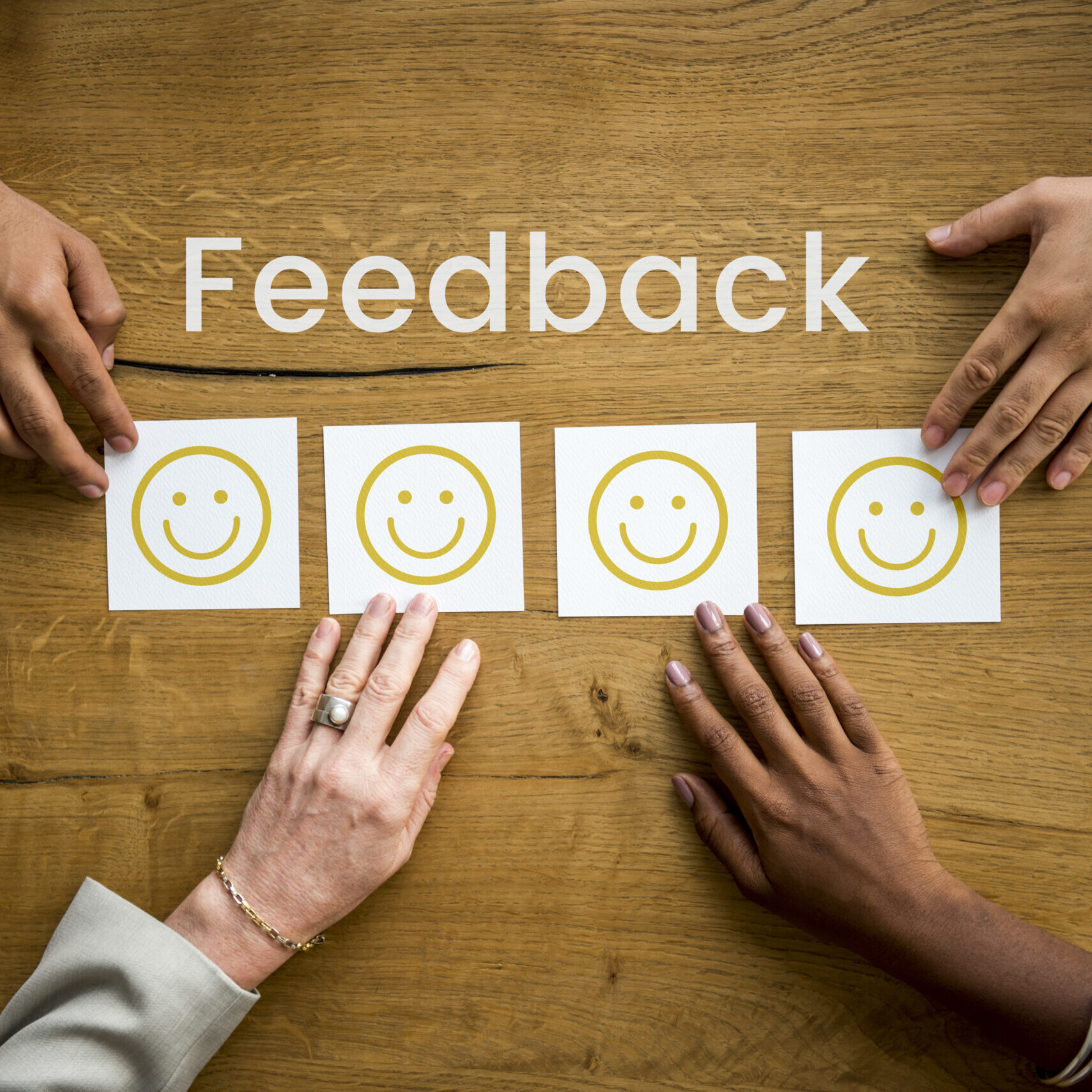 People placing smiley face cards on a table representing real-time feedback and positive evaluations.
